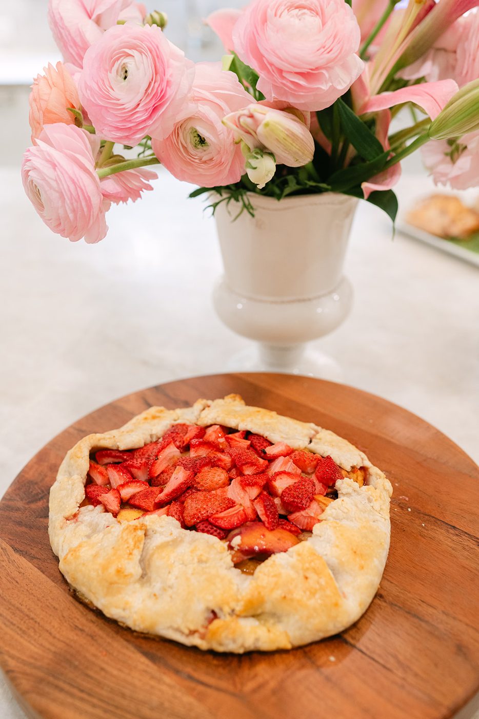 A strawberry galette cooling on a wooden board