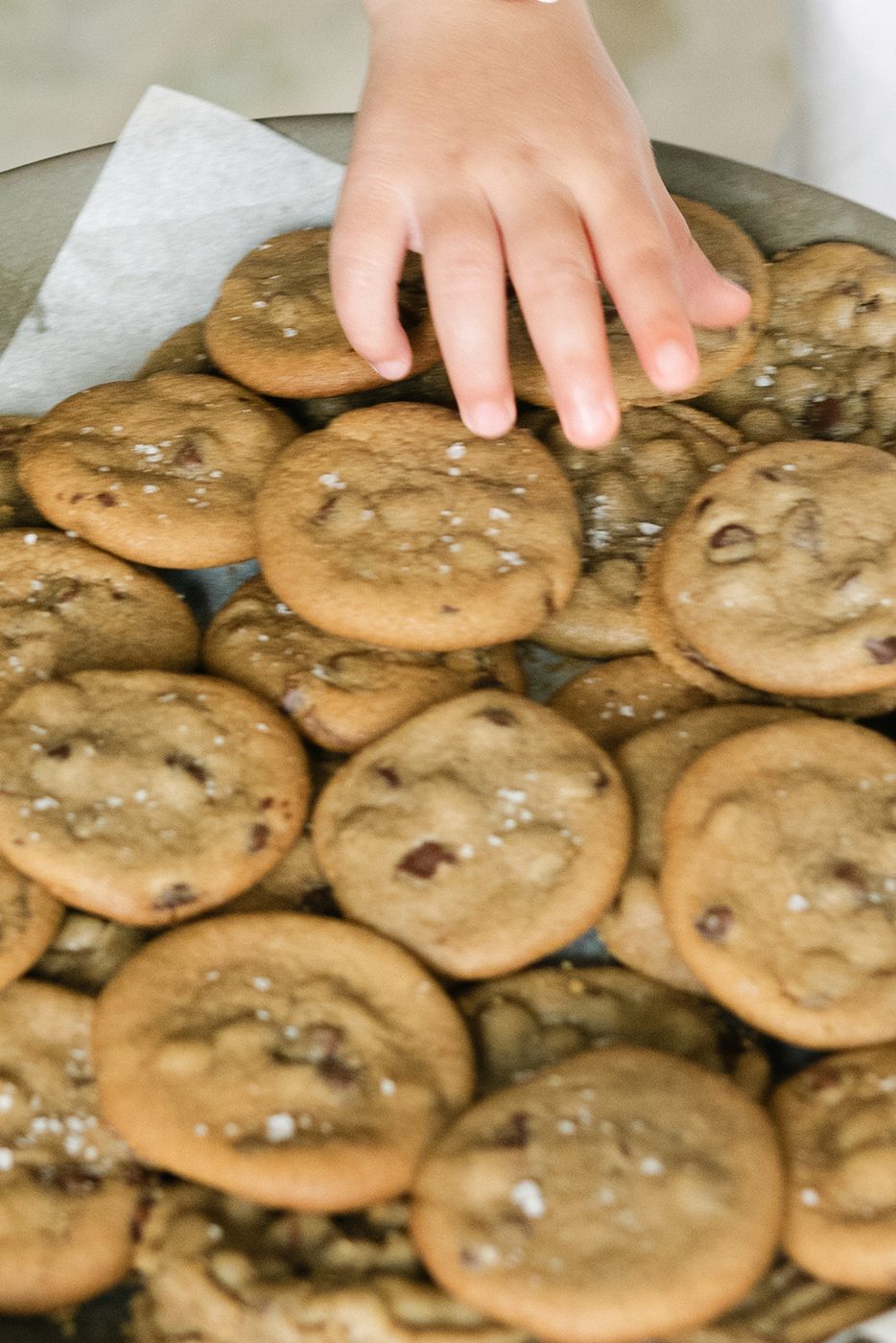 A child reaching for a chocolate chip cookie