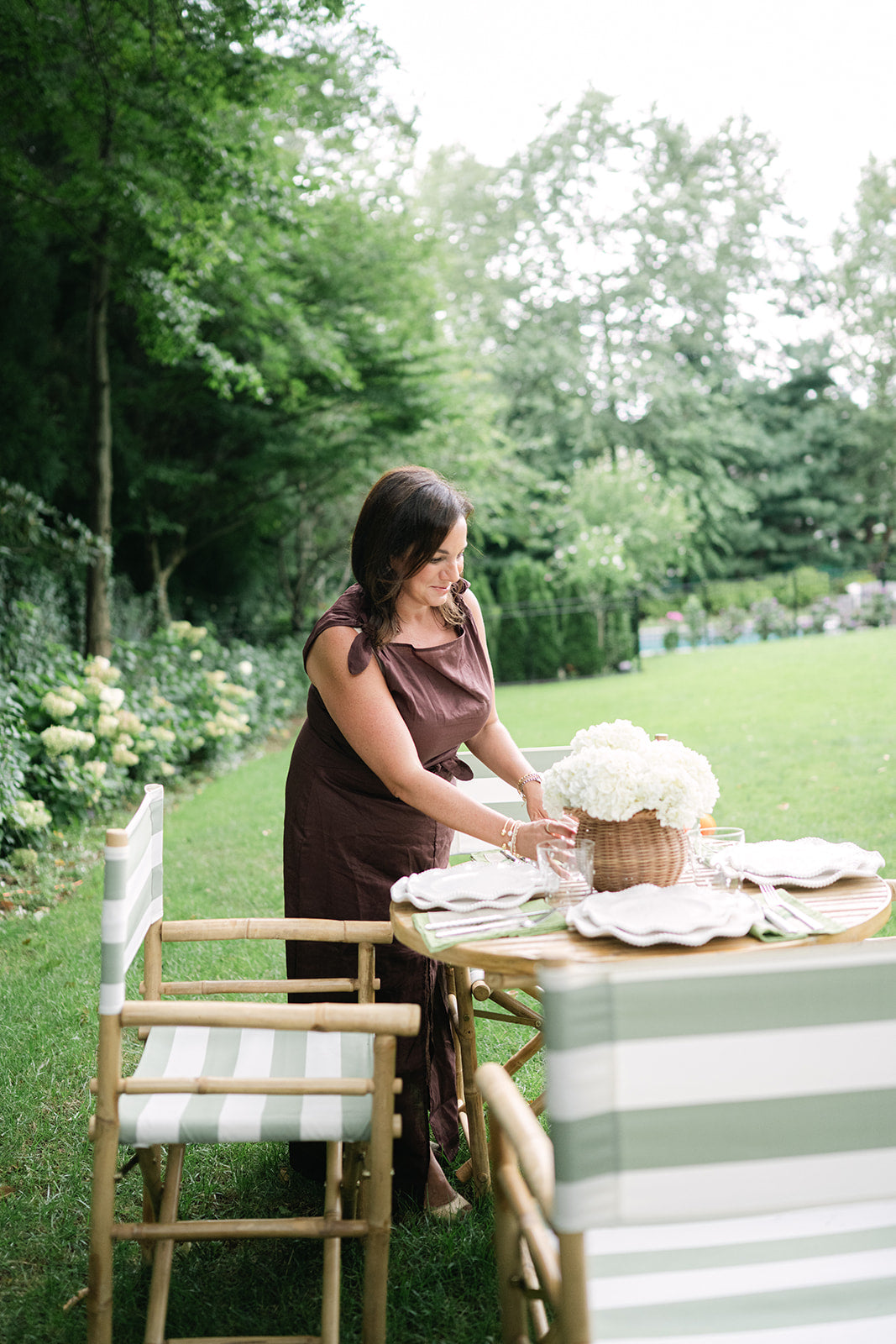 Brittney setting a garden table with white hydrangeas and striped chairs